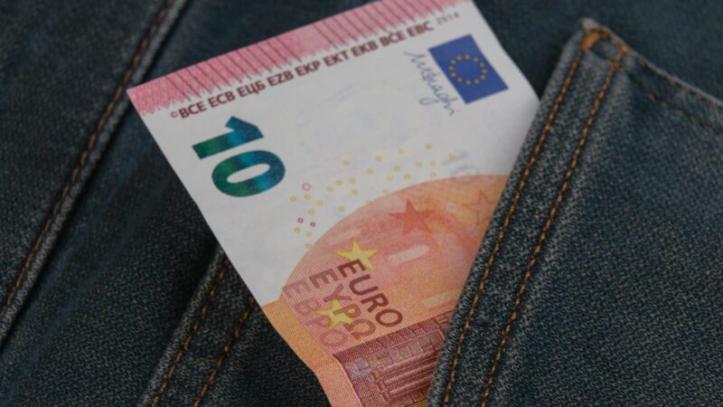 Close-up of a 10 euro banknote sticking out from a denim pocket.